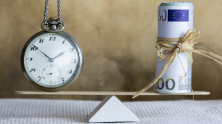 Uhr und Geld auf Waage