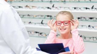 Kind bei der Anprobe einer roten Brille Kinderoptometrie